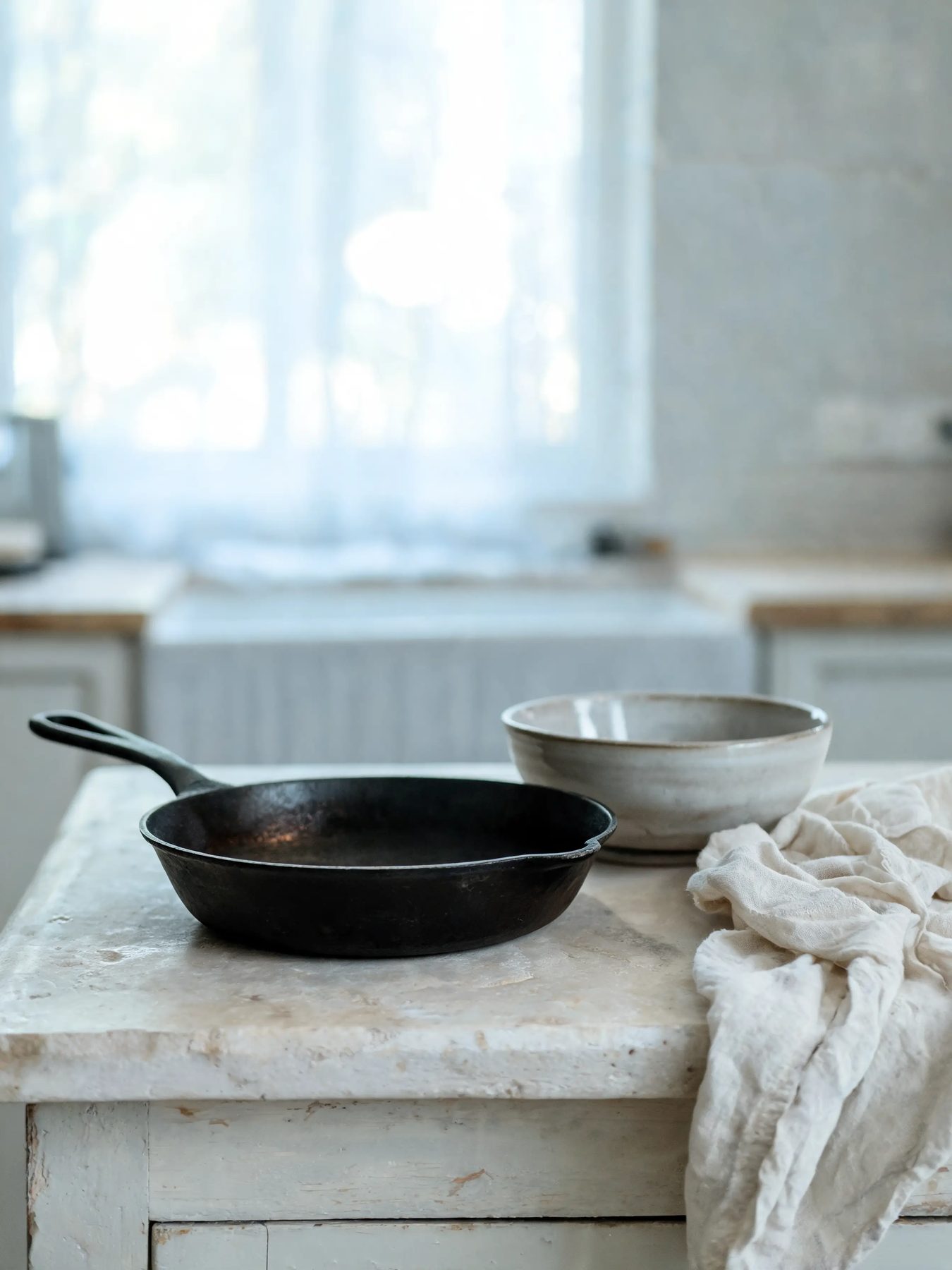Seasoned skillet and glazed stoneware bowl on a limestone counter